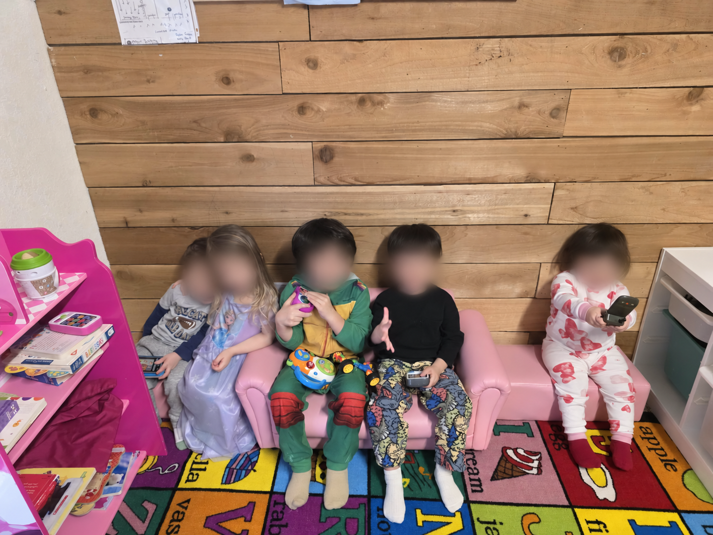 Children relaxing together in the colorful playroom at Hind’s Daycare, with faces blurred for privacy.
