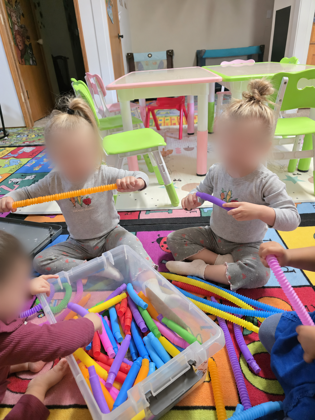 Children exploring colorful sensory tubes, with faces blurred for privacy.